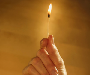 A hand holding a lit match