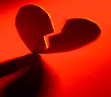 A red cardboard heart cut in half on a red background