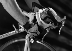 Close up of a man in cycling gloves on a road bike. Photo in black and white.