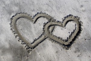 Black and white image of two interlinking hearts in the sand