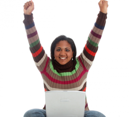 Woman in stripey jumper with her arms in the air and a laptop on her lap