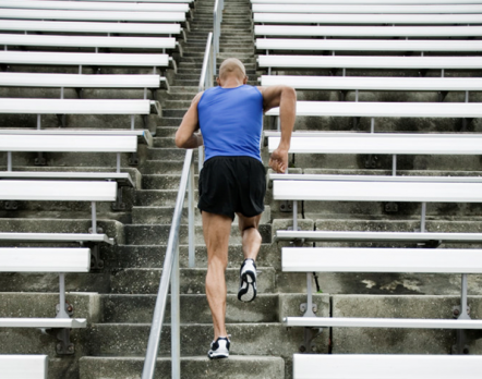 Man in running top and shorts running up stadium steps