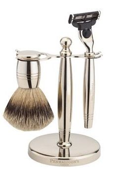 silver shaving brush and silver razor on a silver stand