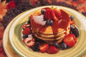 Stack of pancakes with strawberries and blueberries.