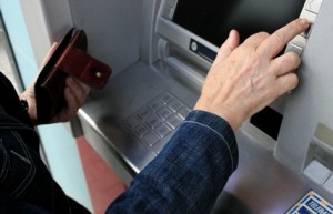 Woman in denim jacket withdrawing money from a cash machine
