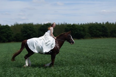 Sophie riding a horse in her wedding dress