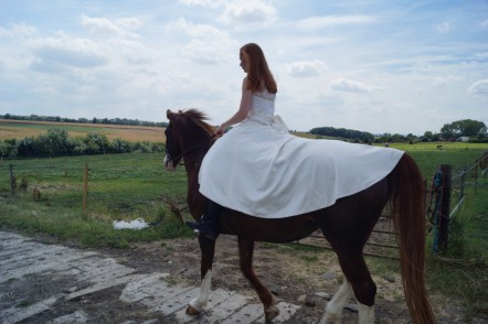 Back view of Sophie riding her horse in her wedding dress
