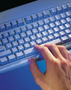 Man typing on a white keyboard under a blue light.