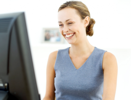 Woman in bluey grey top sitting at a computer
