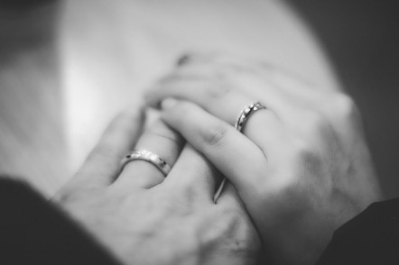 Man and woman holding hands with wedding rings on